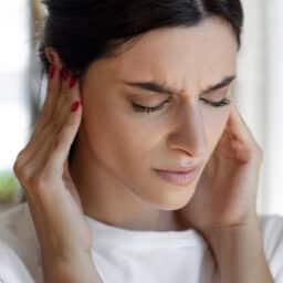 Woman with tinnitus holds ears