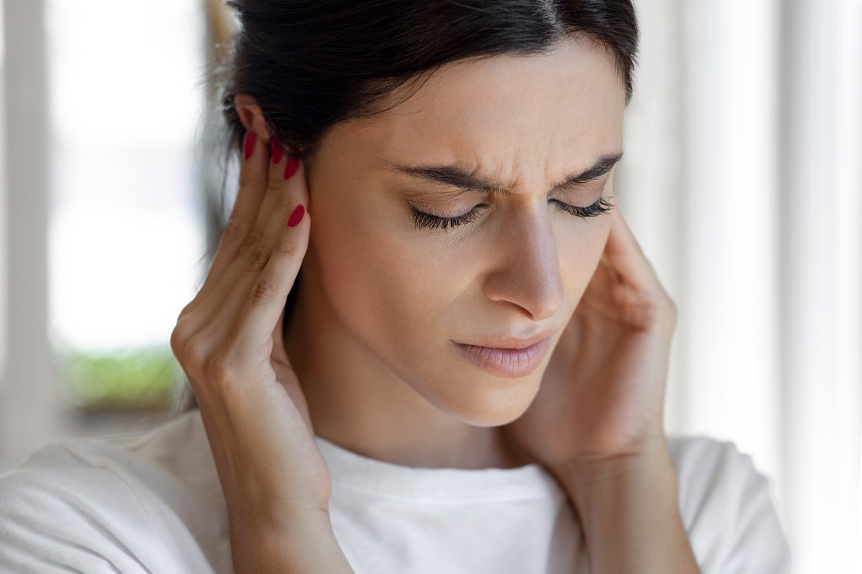 Woman with tinnitus holds ears