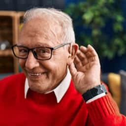 Happy man showing off his hearing aid