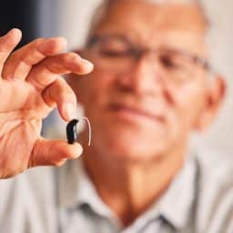 Man holding up his new hearing aid